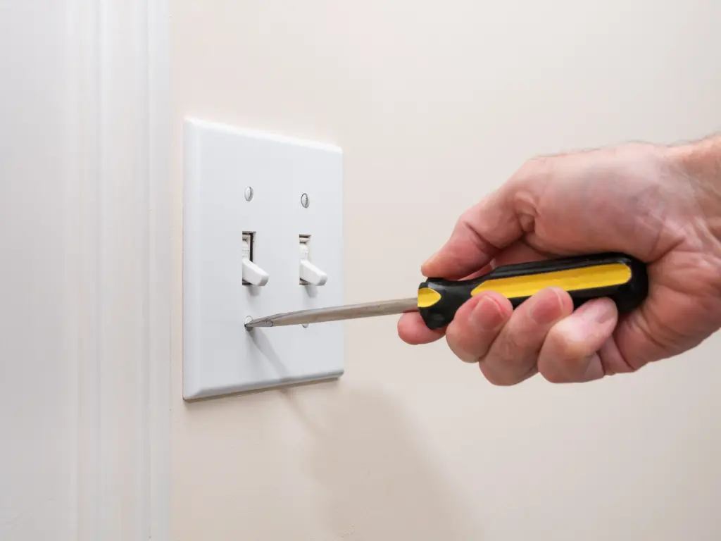 stock-photo-male-electrician-repairing-wall-light-switch-panel-handyman-using-screwdriver-to-install-screw-on-1587076678
