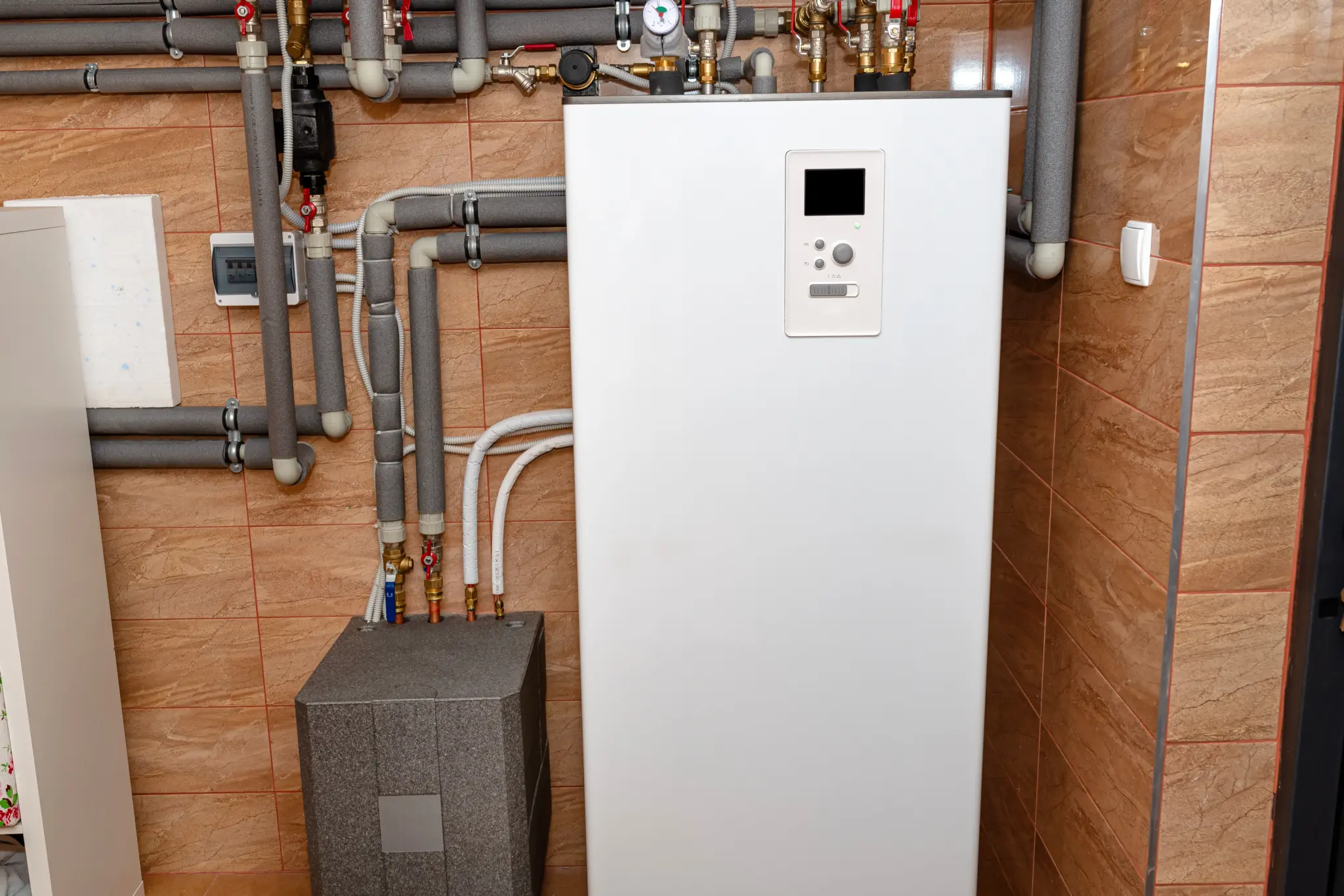 stock-photo-a-modern-air-heat-pump-installed-in-the-home-s-boiler-room-visible-plastic-pipes-and-valves-2389322725