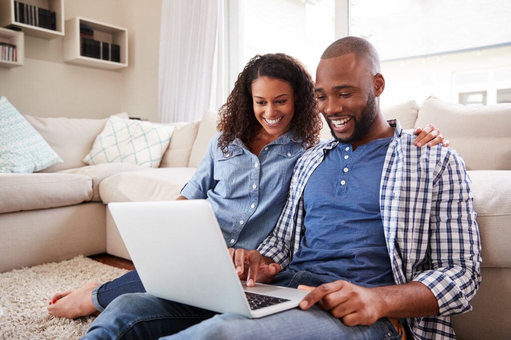 stock-photo-young-black-couple-using-laptop-sitting-on-the-floor-at-home-1070766050
